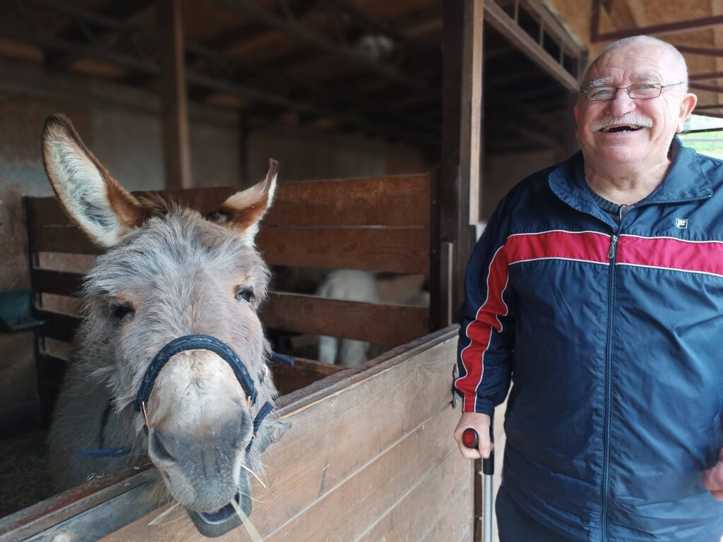 uśmiechnięty podopieczny pozuje do zdjęcia z osiołkiem