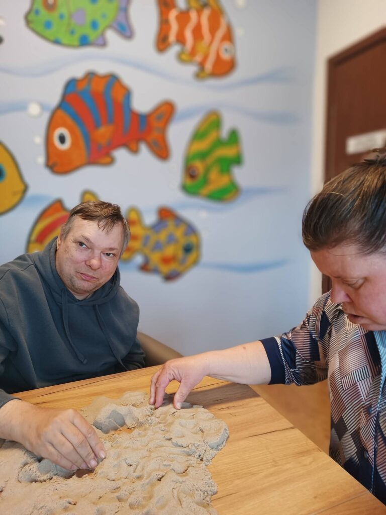 podopieczni tworzą makietę z piasku kinetycznego
