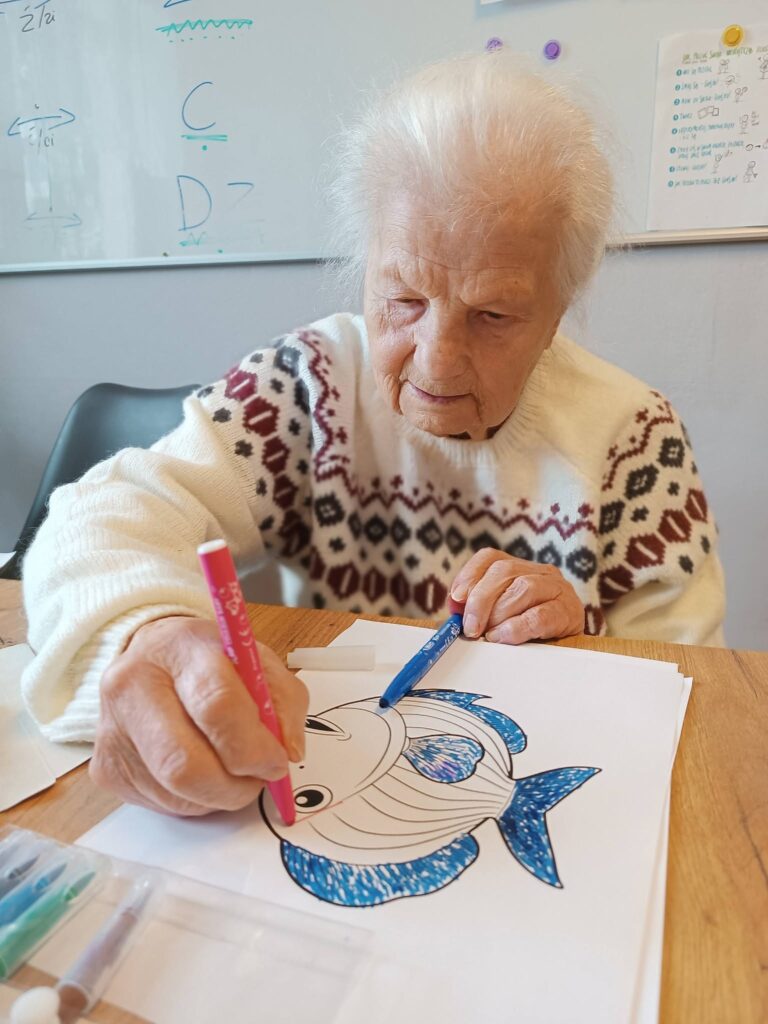 Podopieczna koloruje obrazek z rybą