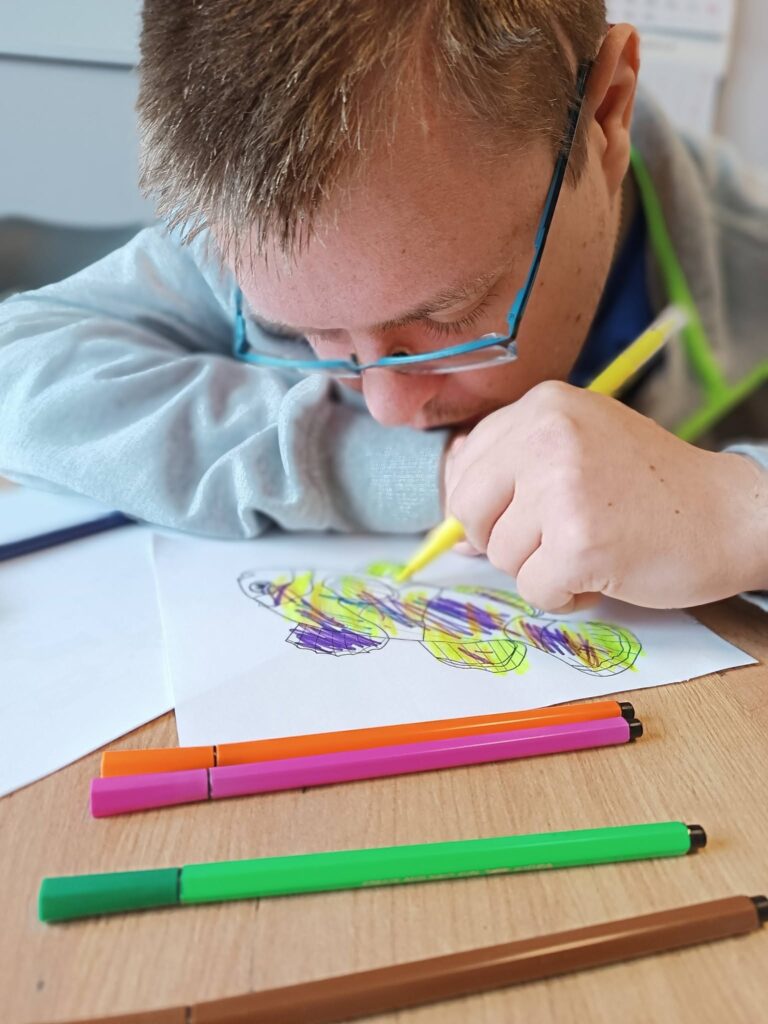 Podopieczny koloruje obrazek z rybą
