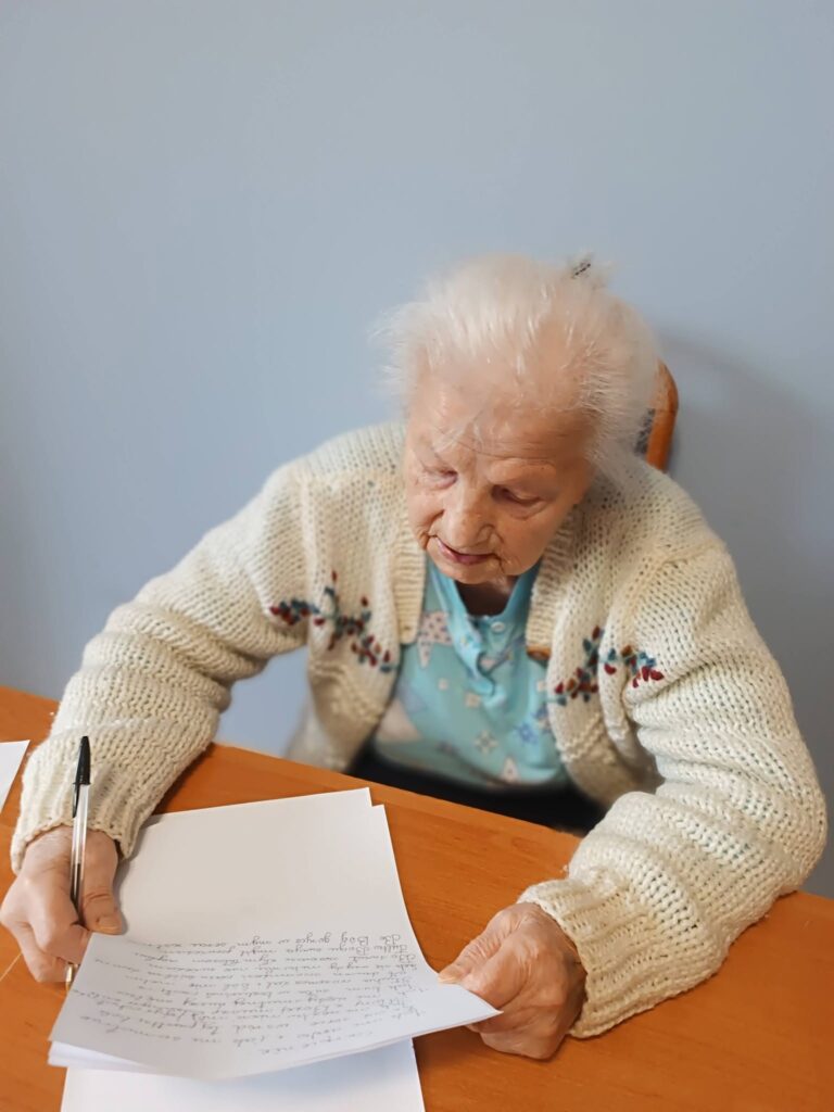 Pani Emilia spisuje na kartce swoją twórczość