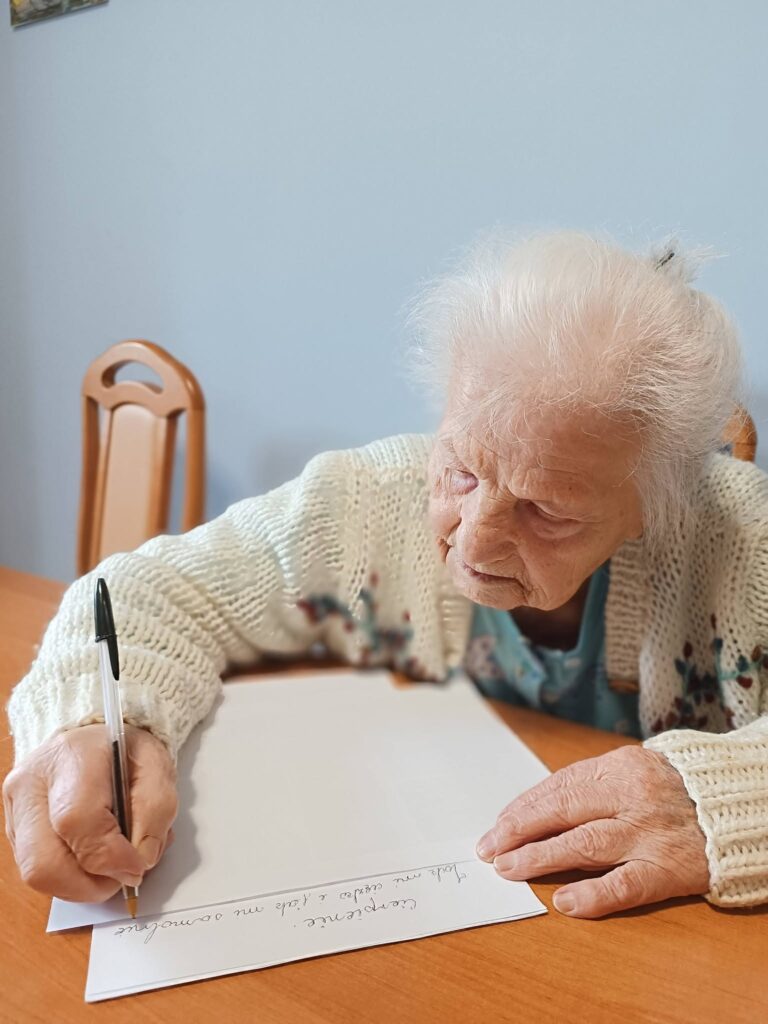 Pani Emilia spisuje na kartce swoją twórczość