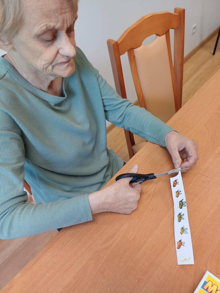 Podopieczna wycina nożyczkami papierowe naklejki z motywem pszczoły