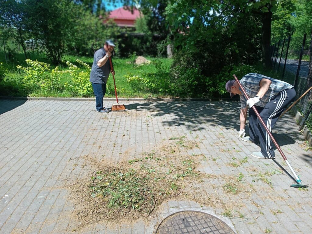Podopieczni sprzątają kostkę na parkingu