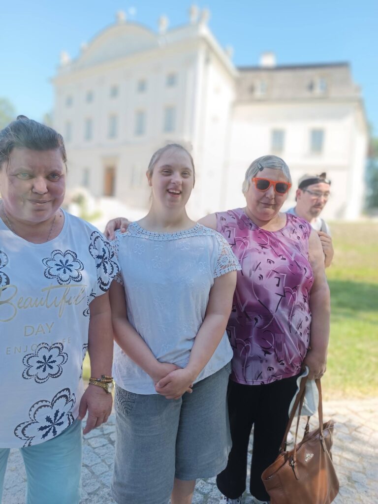 Grupa podopiecznych spaceruje przed pałacem Popielów